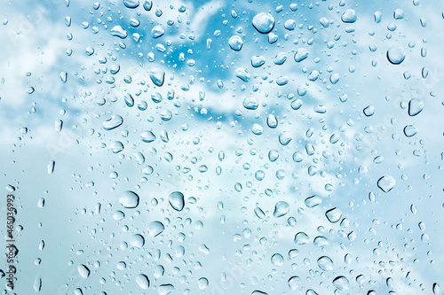 Rain drop on window glass with blue sky and cloud background