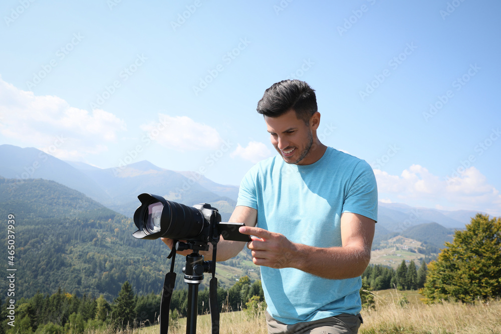 Professional photographer taking picture with modern camera in mountains