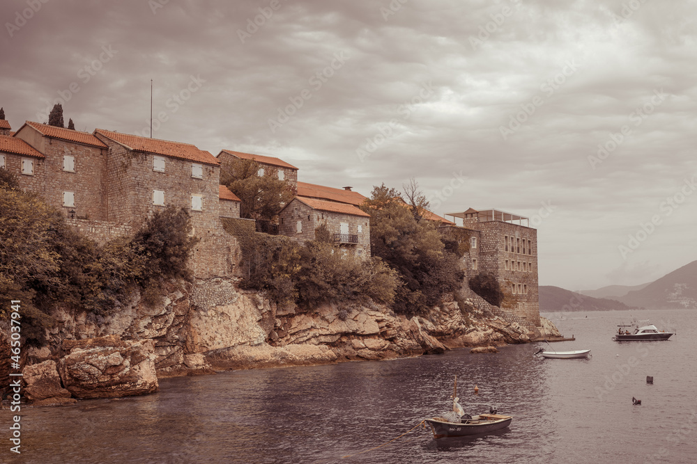 Sveti Stefan, Montenegro- September, 2021: summer sunset on Beach. Resort includes the islet of Sveti Stefan and part of the mainland. Ancient houses and plants from medieval times. Dark brown toning