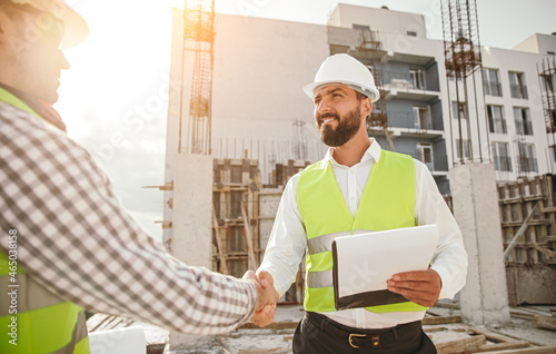 Engineers shaking hands at construction site photo