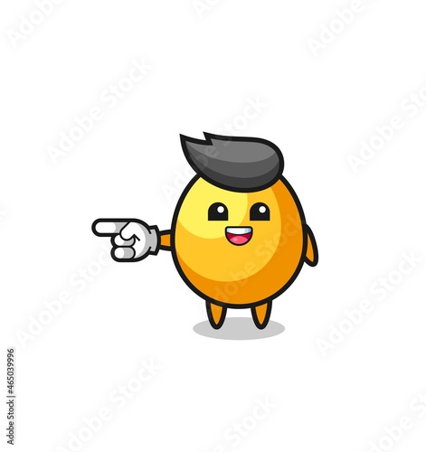 golden egg cartoon with pointing left gesture © heriyusuf