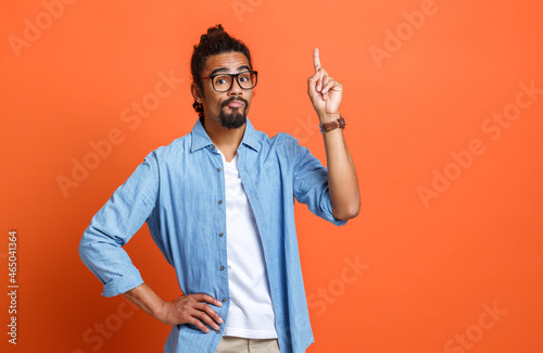 Young serious african american man in casual clothes pointing up at copy space with forefinger