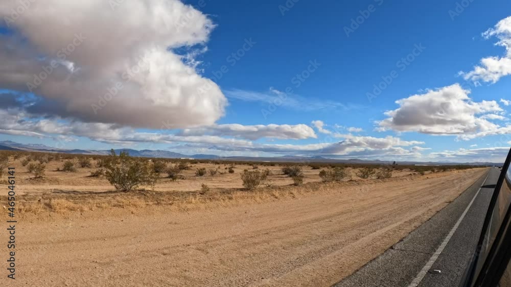 The Mojave Desert as seen from the car's side view mirror on a day with clouds over the barren wasteland The Mojave Desert as seen from the car's side view mirror on a day with clouds over the barren wasteland