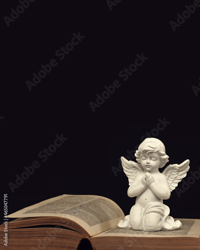 Condolence card with an angel and open book, dark background with copy space