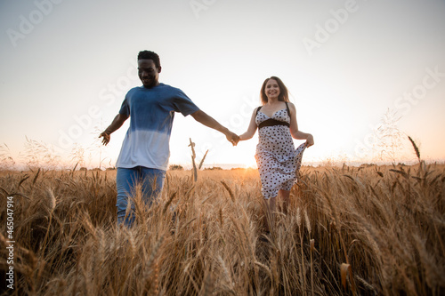 Young adult couple holding hands while walking in field