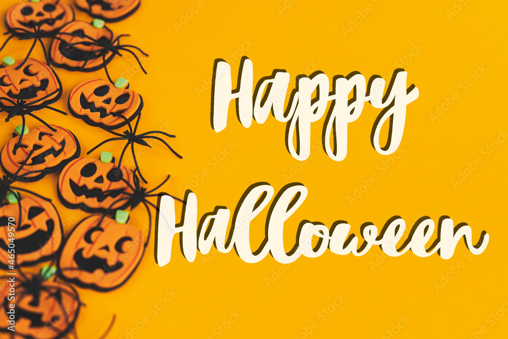 Happy Halloween text sign on pumpkins jack o lanterns, spiders border on orange background. Season's greeting card. Handwritten happy halloween text. Trick or treat