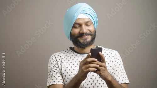 Happy smiling sikh man while chatting on mobile phone - concept showing of social media, internet or using online dating app. photo