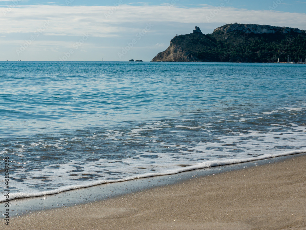 view from the beach with waves on the shore of the Sella del Diavolo mountain