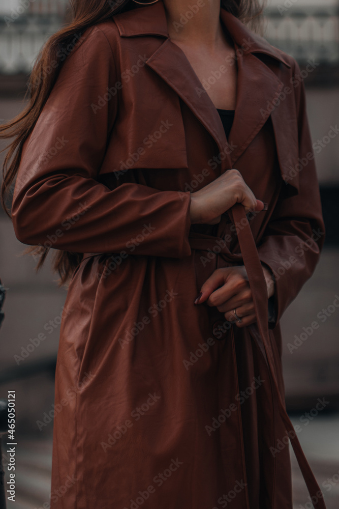 Autumn fashionable female outfit. Stylish woman walking in brown coat outdoors. Trendy modern clothes. Street style fashion