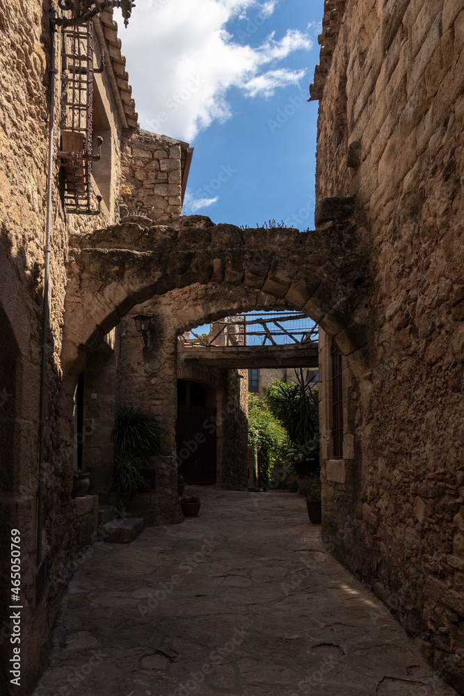 narrow stone street with an arch in the medieval village of pals on a summer day
