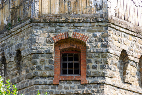 Red brick window of an ancient castle in a wall of natural gray stone. Arched construction. Summer sunny day. Close-up © ALEKSEI