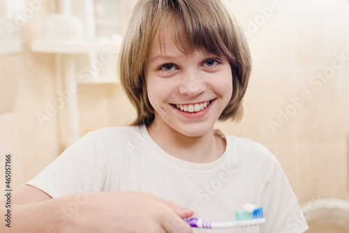 Cheerful young boy cleaning teeth with toothpaste and toothbrush in bathroom