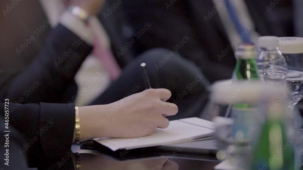 female writing notes on a small notepad in meeting room female writing notes on a small notepad in meeting room
