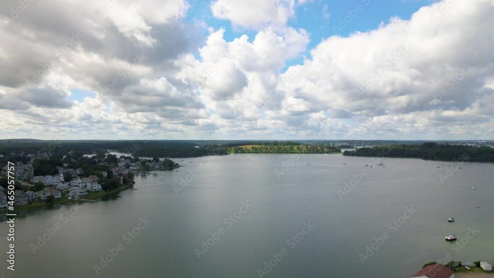 Aerial static shot of wide bay area on water with coastline of houses. Slow moving clouds towards camera. Aerial static shot of wide bay area on water with coastline of houses. Slow moving clouds towards camera.