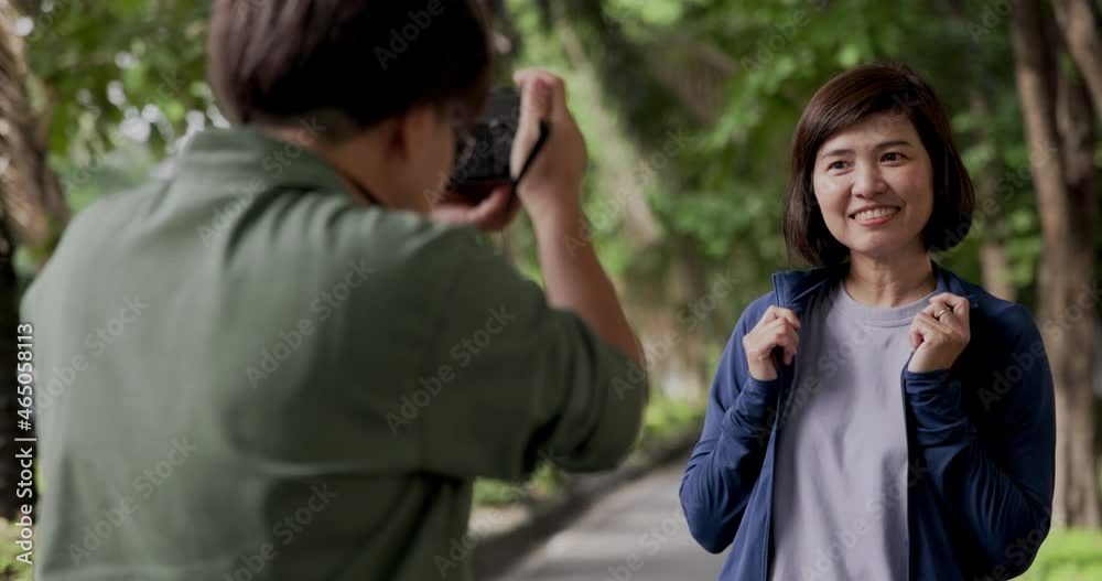 Asian female couple using mirrorless camera stand in park practicing photography during holidays with smile and happiness. Living a life that feels relaxed in summer. freedom of life. Concept gadget Asian female couple using mirrorless camera stand in park practicing photography during holidays with smile and happiness. Living a life that feels relaxed in summer. freedom of life. Concept gadget
