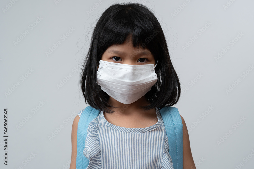 Portrait of Asian girl kid with protective face mask and school backpack ready for new school year with pandemic restrictions. Concept of kid going back to school and new normal lifestyle Portrait of Asian girl kid with protective face mask and school backpack ready for new school year with pandemic restrictions. Concept of kid going back to school and new normal lifestyle