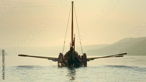 Vikings Sail on an Old Ship with a Lowered Sail on a Quiet River in the Fog. Concept on the theme of the Vikings and the early Middle Ages.