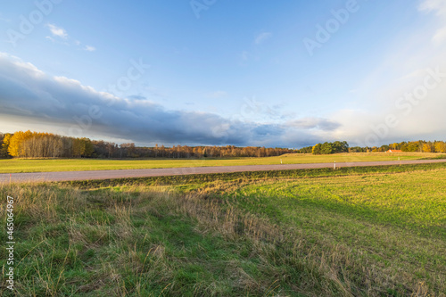 Beautiful autumn nature landscape view. Highway between green fields on blue sky background. Sweden. 