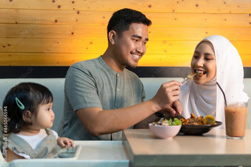 Fototapeta Young malay couple at the restaurant smiling and enjoying their food