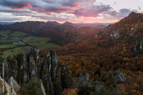 Scenic landscape in Sulov, Slovakia, on beautiful autumn sunrise with colorful leaves on trees in forest and bizarre pointy rocks on mountains and slight mist in the valleys and dramatic clouds on sky