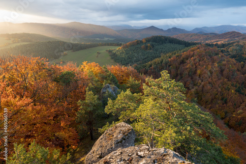 Scenic landscape in Sulov, Slovakia, on beautiful autumn sunrise with colorful leaves on trees in forest and bizarre pointy rocks on mountains and slight mist in the valleys and dramatic clouds on sky © Michal
