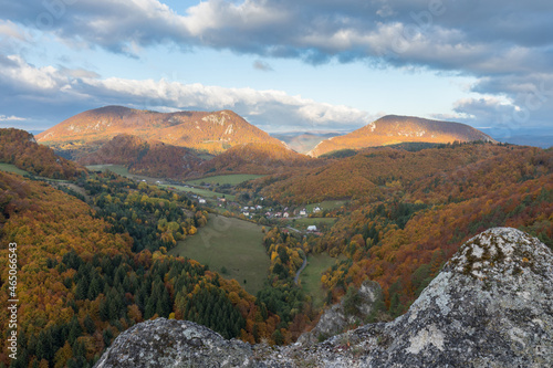 Scenic landscape in Sulov, Slovakia, on beautiful autumn sunrise with colorful leaves on trees in forest and bizarre pointy rocks on mountains and slight mist in the valleys and dramatic clouds on sky