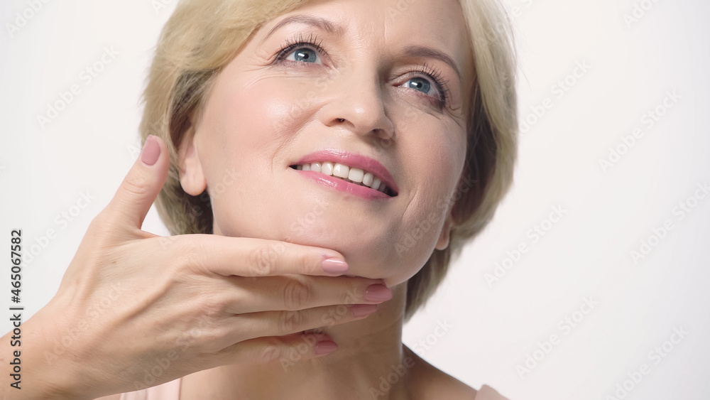 happy middle aged woman with perfect skin touching face isolated on white. happy middle aged woman with perfect skin touching face isolated on white.