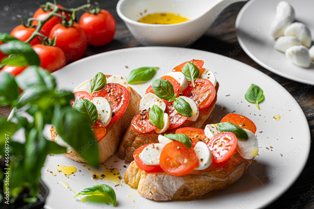 bruschetta caprese. fresh basil leaves, ripe aromatic tomatoes and Italian mozzarella on bruschetta, drizzled with olive oil and sprinkled with pepper and herbs.
