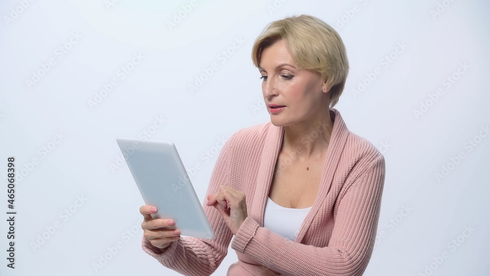 mature blonde woman using digital tablet isolated on white.