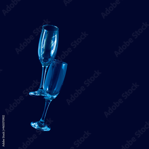 two glasses of champagne with neon blue lights. modern futurism 2022 year background. minimalism. surrealism. creative decoration idea with copyspace