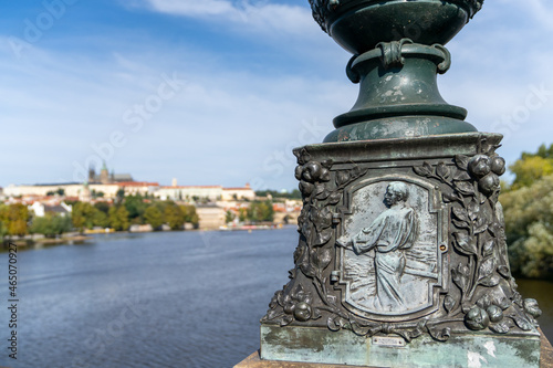 view of the Vltava River and Prague Castle with a bridge pillar and sculpture in the foreground
