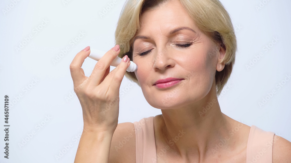 mature woman with closed eyes using anti-wrinkle gel roller isolated on white. mature woman with closed eyes using anti-wrinkle gel roller isolated on white.