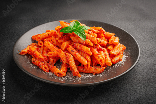 Close-up of a plate of freshly cooked Penne all'Arrabbiata pasta on a dark background photo