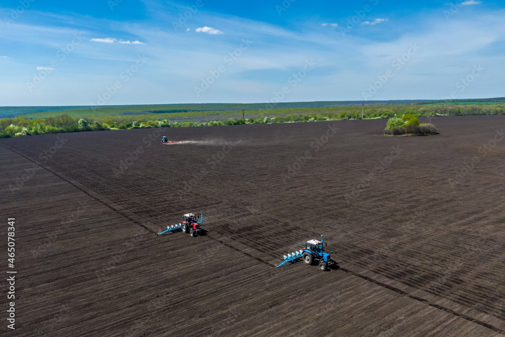 Farmer seeding, sowing crops at field. process of planting seeds in the ground. spring time agricultural activities. Drone photo