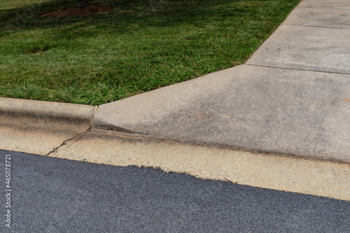 Specially formed concrete curb turning into a concrete drive, manicured grass and asphalt street bed, horizontal aspect © Natalie Schorr