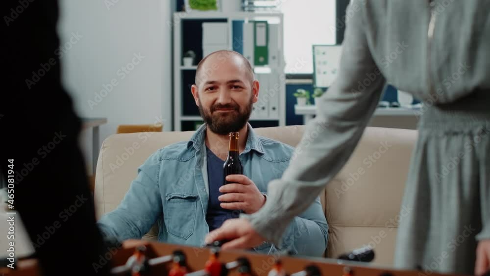 custom made wallpaper toronto digitalPortrait of businessman holding bottle of beer after work at office. Person looking at colleagues playing football game at foosball table to have fun with activity. Man with drink