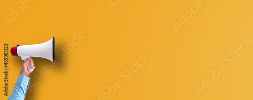 hand holding megaphone against orange background with copy space, marketing concept