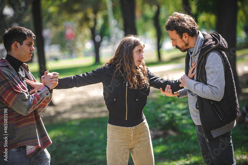 Woman with outstretched arms tries to separate men in quarrel