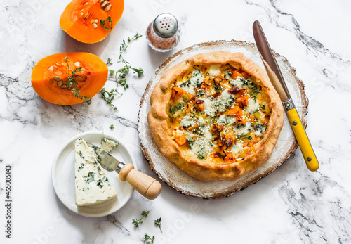 Delicious seasonal pastries - honey pumpkin, leek, gorgonzola cheese quiche on a light background, top view photo