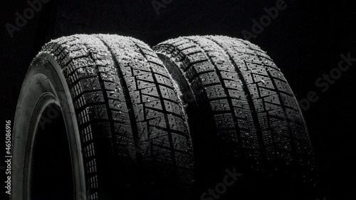 Winter Car tires with snow close-up wheel profile structure on black background. 