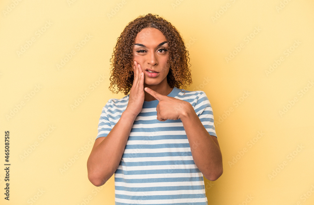 Young latin transsexual woman isolated on yellow background having a strong teeth pain, molar ache.
