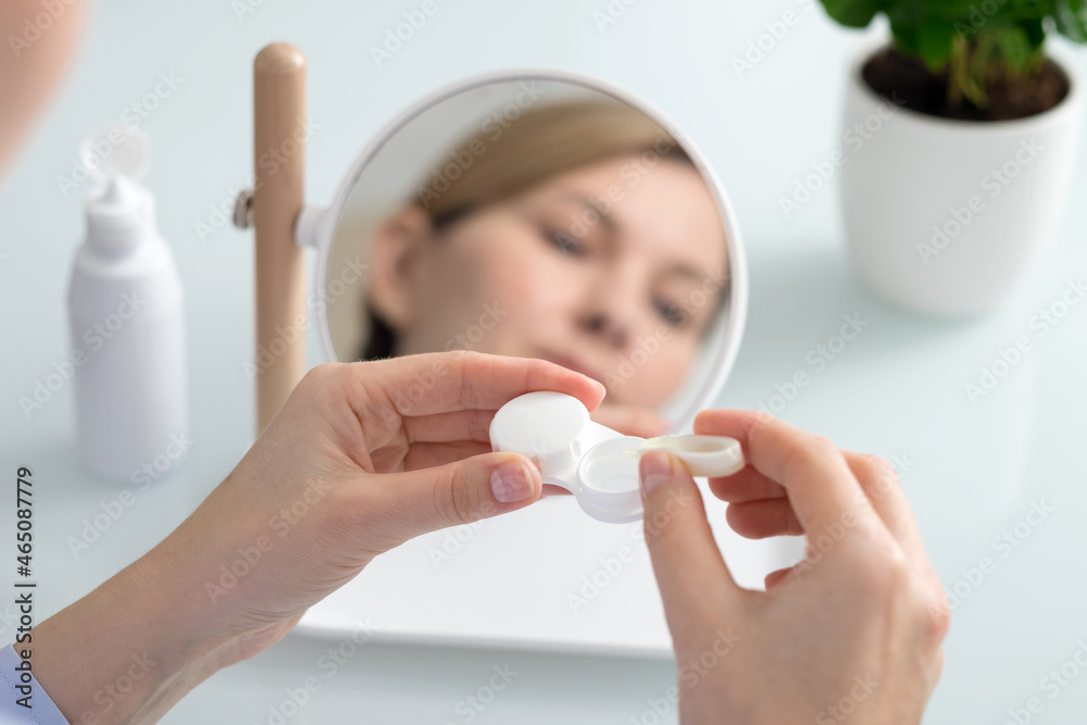 A woman holds a contact lens container in her hands A woman holds a contact lens container in her hands