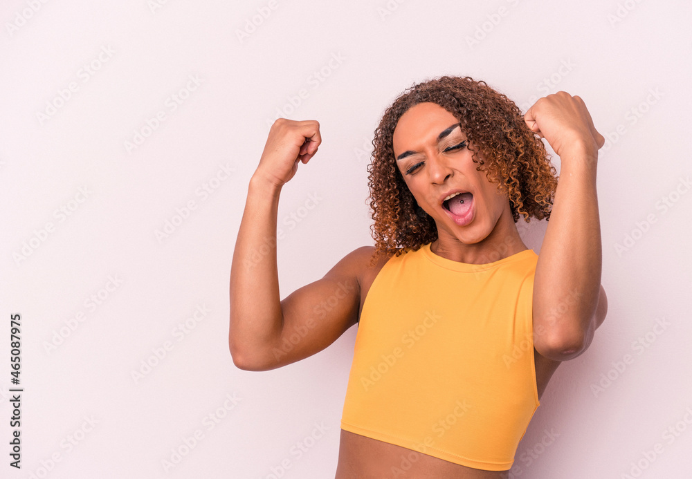 Young latin transsexual woman isolated on pink background raising fist after a victory, winner concept. Young latin transsexual woman isolated on pink background raising fist after a victory, winner concept.