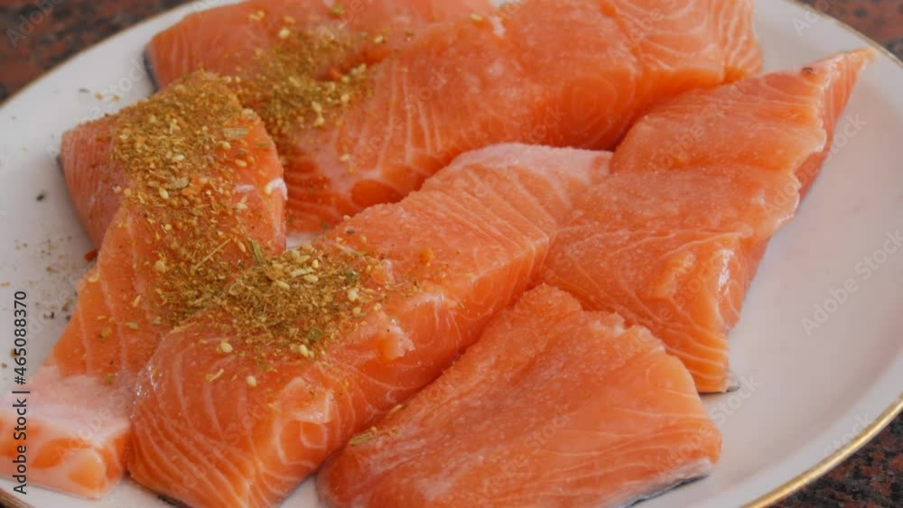 Huge fillet of red fish salmon cut into pieces sprinkle with peppercorn seasoning on a plate