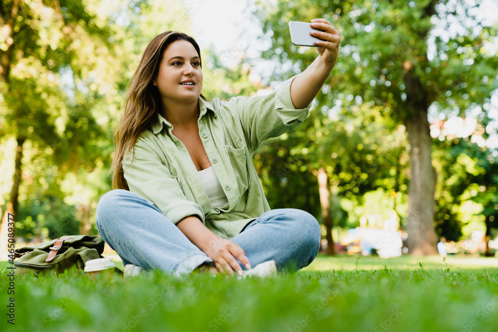 Smiling caucasian student freelancer having video call conversation on smart phone, taking selfie, vlogging, blogging on mobile application, social media posting in park Smiling caucasian student freelancer having video call conversation on smart phone, taking selfie, vlogging, blogging on mobile application, social media posting in park