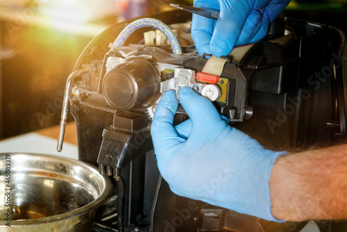 A repairman repairs a broken coffee maker