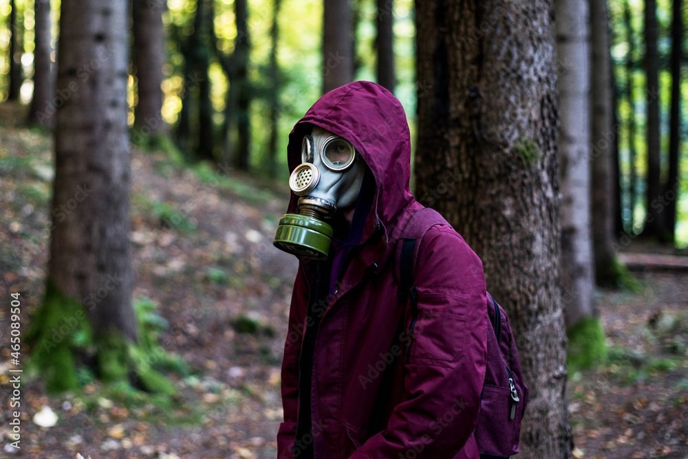 casual young man in a gas mask standing on the forest. Ecological catastrophy. Post apocalyptic survivor in gas mask. Man at forest. casual young man in a gas mask standing on the forest. Ecological catastrophy. Post apocalyptic survivor in gas mask. Man at forest.