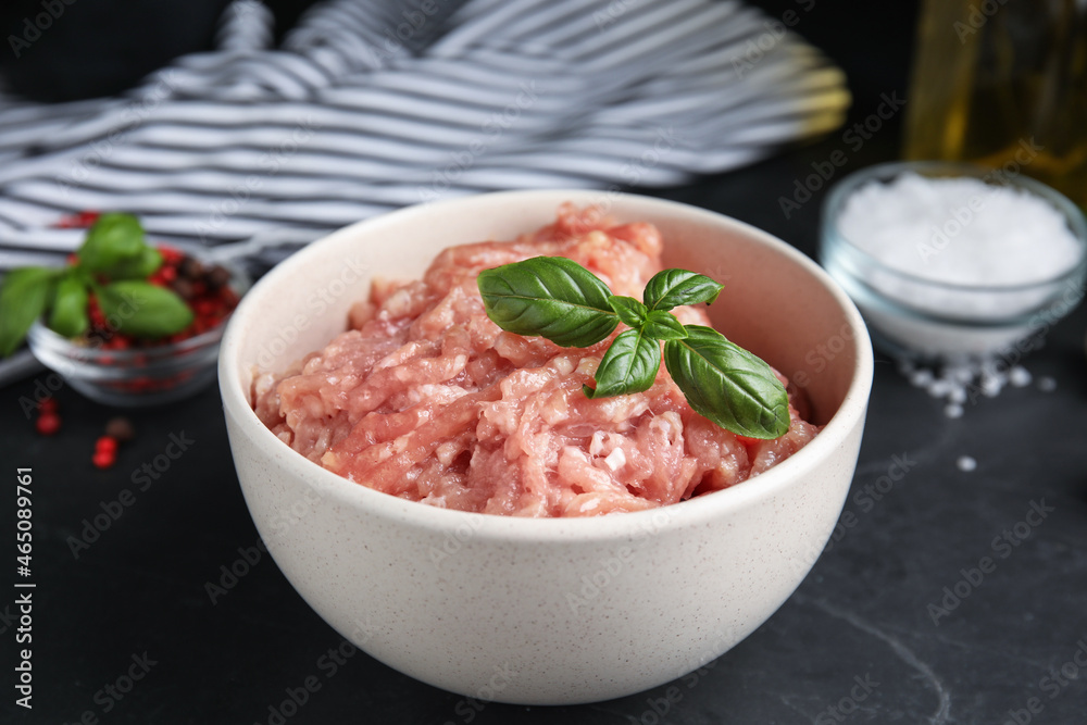 Raw chicken minced meat with basil on black table, closeup