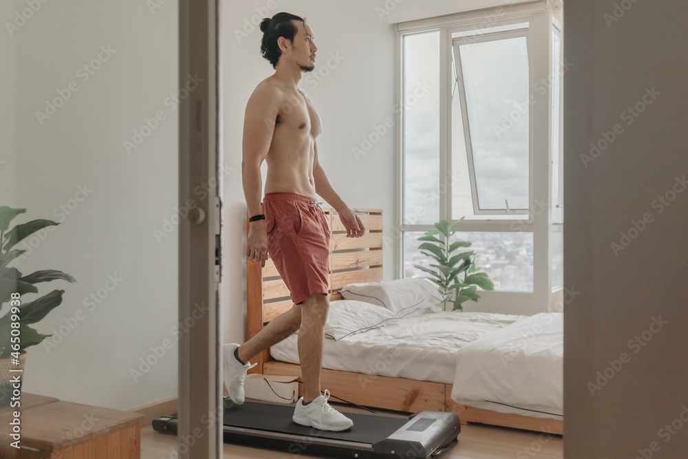 Asian man exercise by walking on the treadmill in his apartment. Asian man exercise by walking on the treadmill in his apartment.