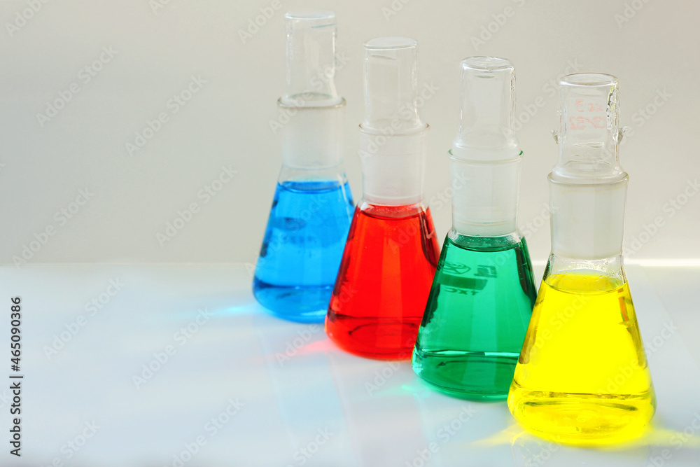 four chemical flasks with a multi-colored liquid are used in the analytical laboratory for research